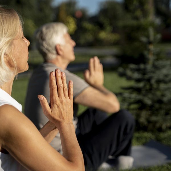 side-view-older-couple-practicing-yoga-outdoors